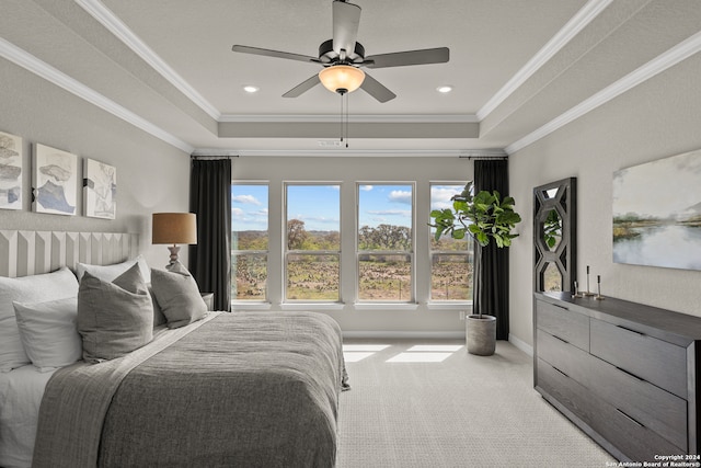 bedroom featuring light carpet, crown molding, a tray ceiling, and ceiling fan