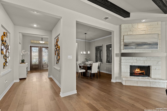 entryway with an inviting chandelier, ornamental molding, hardwood / wood-style flooring, and a fireplace