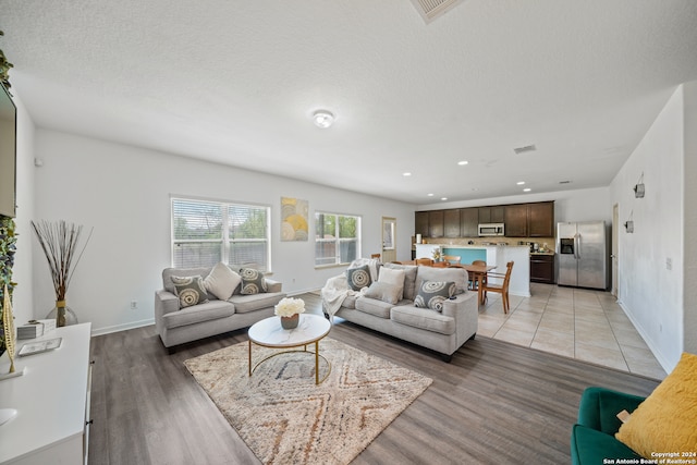 living room with a textured ceiling and light wood-type flooring