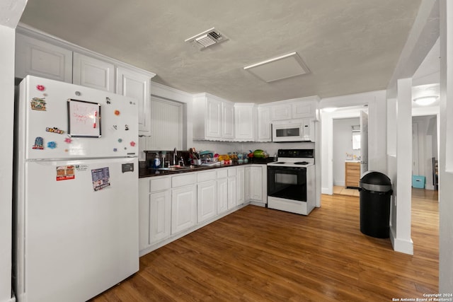 kitchen featuring a sink, visible vents, wood finished floors, and white appliances