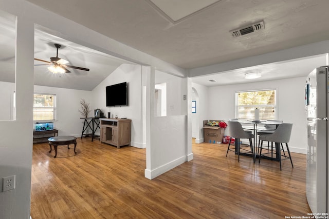 dining area with wood finished floors, visible vents, a healthy amount of sunlight, and vaulted ceiling