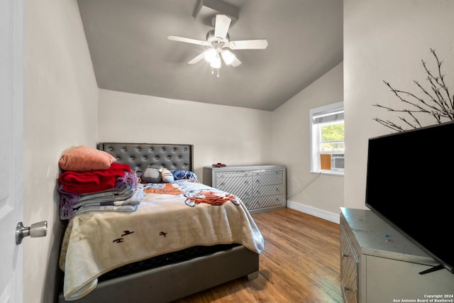bedroom with a ceiling fan, vaulted ceiling, wood finished floors, and baseboards