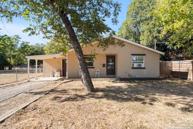 view of front facade featuring a patio, driveway, a carport, stucco siding, and fence