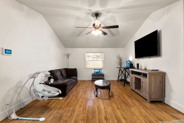 living area with baseboards, ceiling fan, light wood-style floors, and lofted ceiling