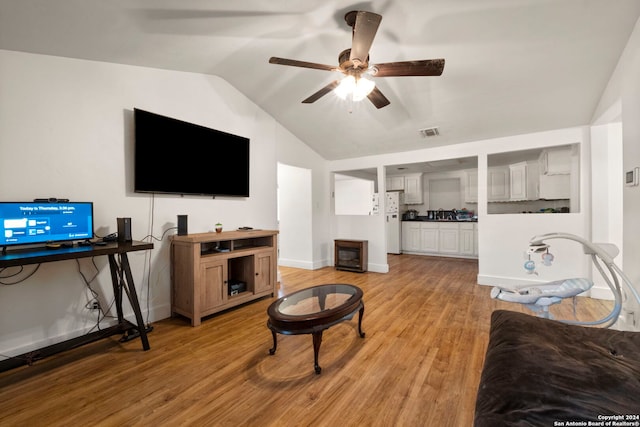 living area featuring vaulted ceiling, light wood finished floors, baseboards, visible vents, and a ceiling fan