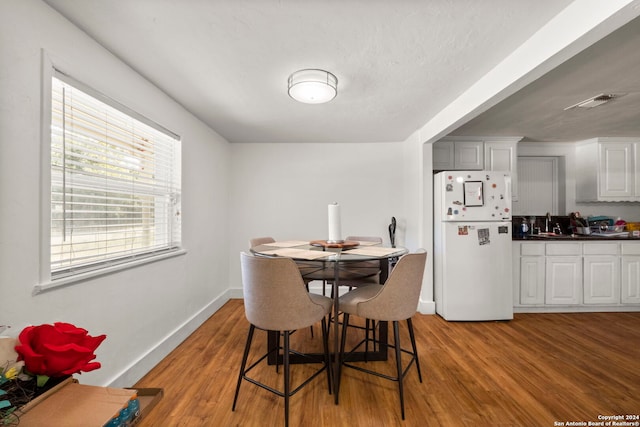 dining area with visible vents, light wood-style flooring, and baseboards