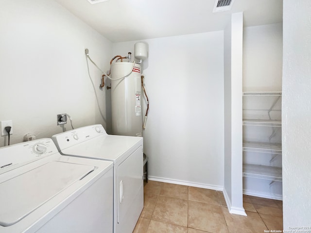 washroom featuring electric water heater, separate washer and dryer, and light tile patterned floors