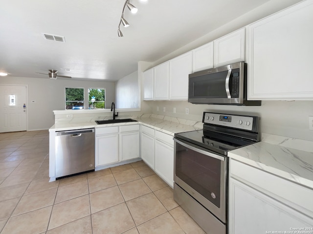 kitchen featuring kitchen peninsula, stainless steel appliances, sink, light tile patterned flooring, and white cabinets