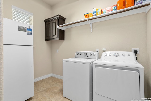 clothes washing area with washing machine and dryer and cabinets