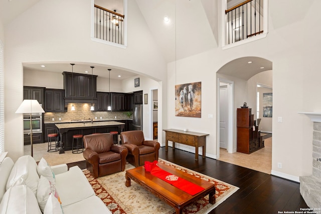 living room featuring sink, light hardwood / wood-style floors, and high vaulted ceiling