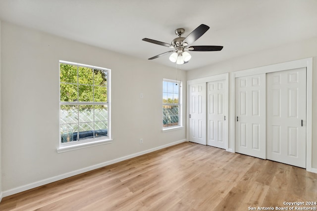 unfurnished bedroom with multiple closets, light wood-type flooring, and ceiling fan