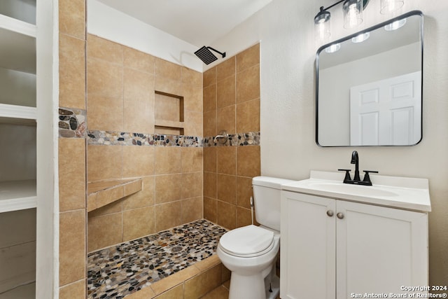 bathroom with vanity, toilet, and tiled shower