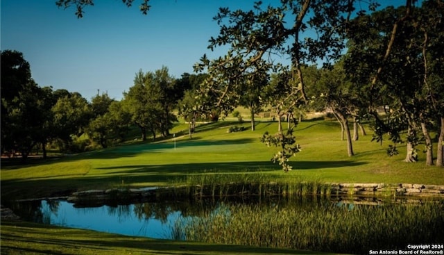 view of property's community with a water view and a lawn