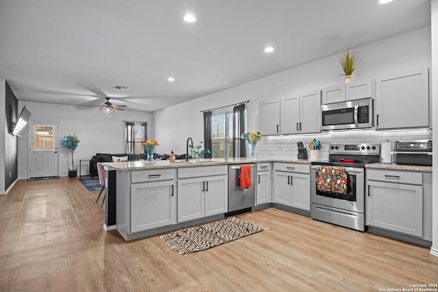 kitchen featuring kitchen peninsula, stainless steel appliances, sink, light hardwood / wood-style floors, and ceiling fan