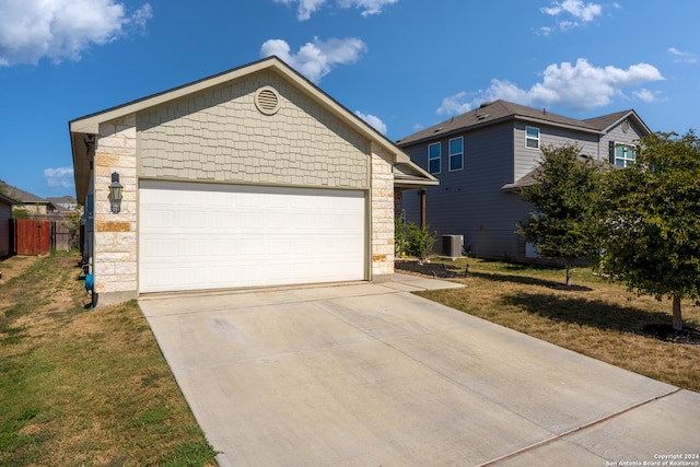 view of front facade with a front yard, central AC, and a garage