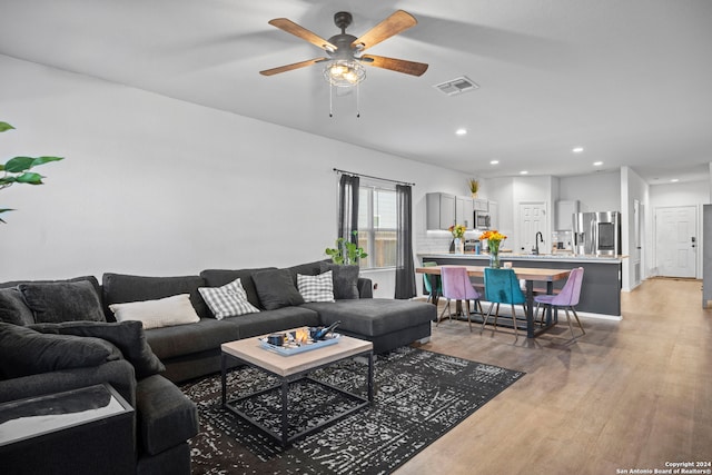 living room featuring sink, ceiling fan, and light hardwood / wood-style flooring