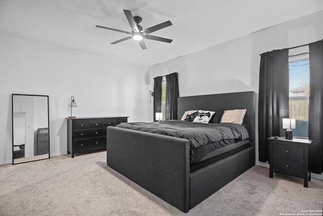 bedroom featuring ceiling fan, light carpet, and multiple windows