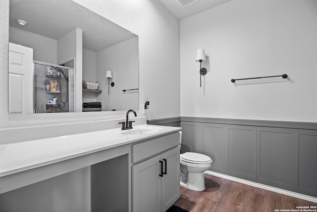 bathroom featuring vanity, toilet, walk in shower, and hardwood / wood-style floors