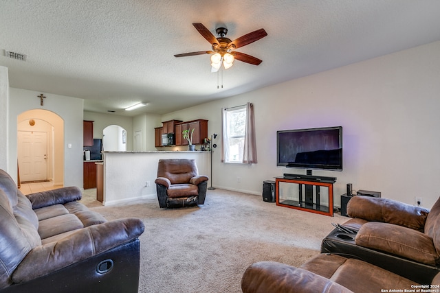 living room featuring ceiling fan, a textured ceiling, and light colored carpet