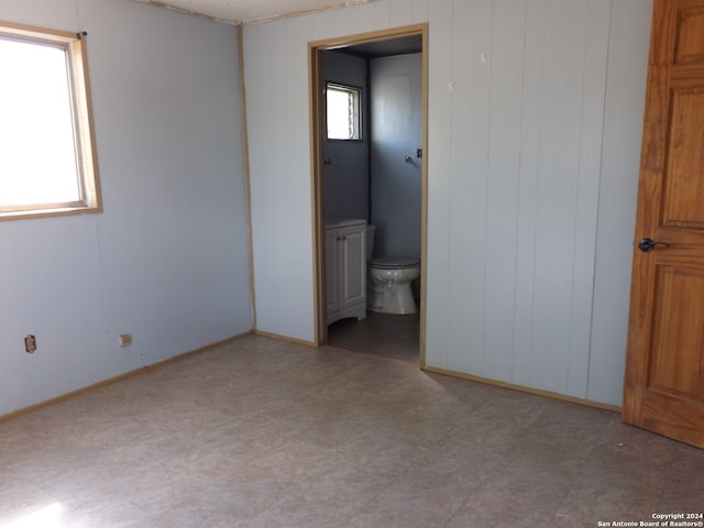 unfurnished bedroom with wooden walls and ensuite bath