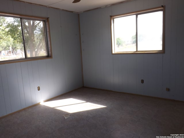 unfurnished room with ceiling fan and wood walls