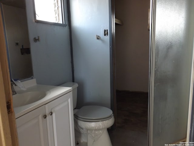 bathroom with toilet, an enclosed shower, and vanity