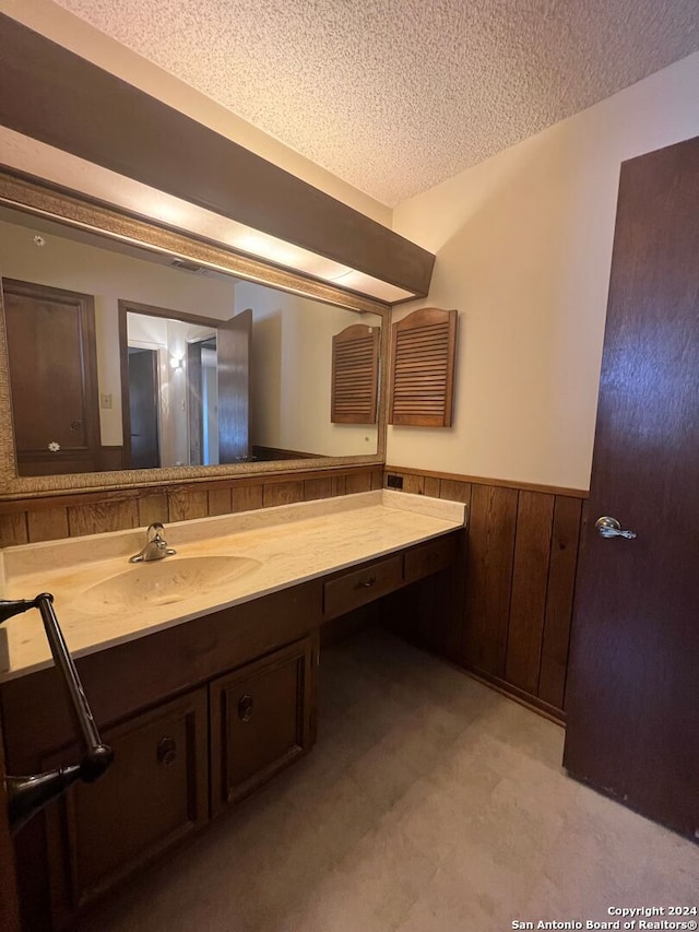 bathroom featuring vanity, wood walls, and a textured ceiling