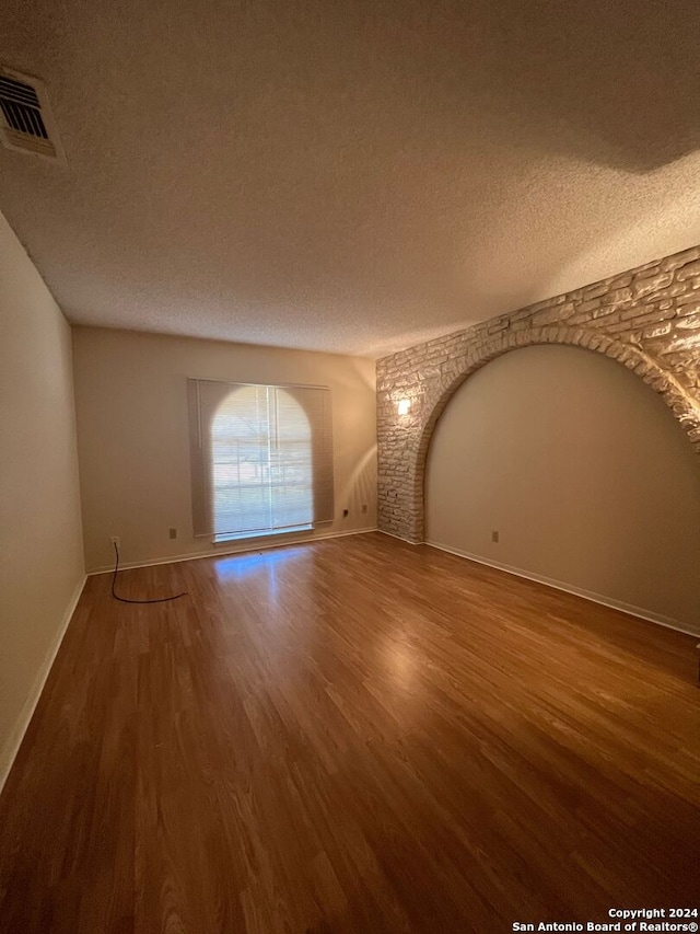 spare room featuring a textured ceiling and hardwood / wood-style floors