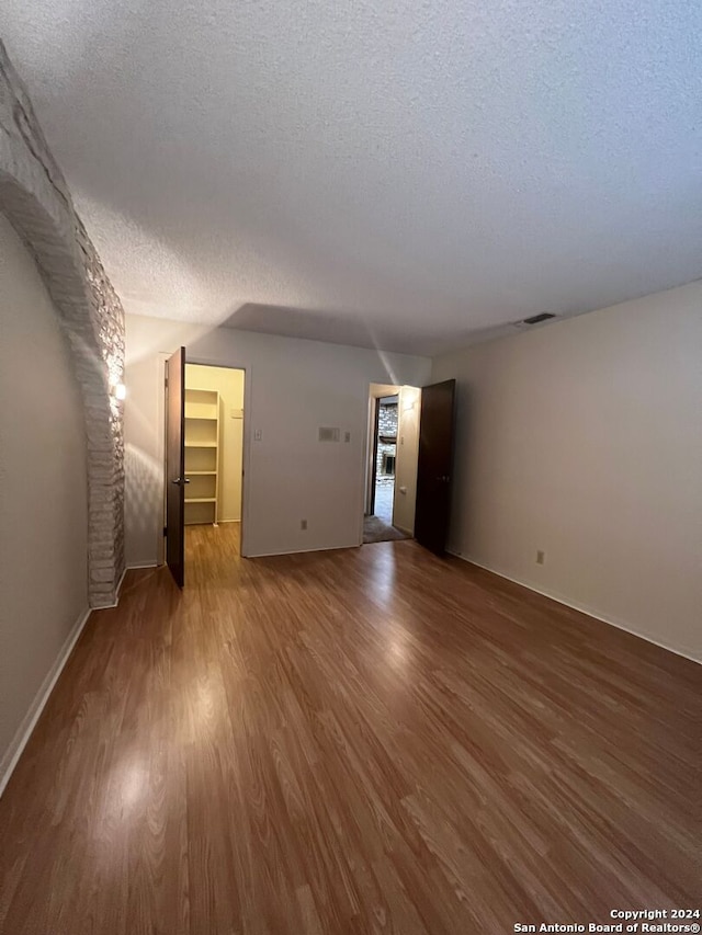 unfurnished living room featuring a textured ceiling and wood-type flooring