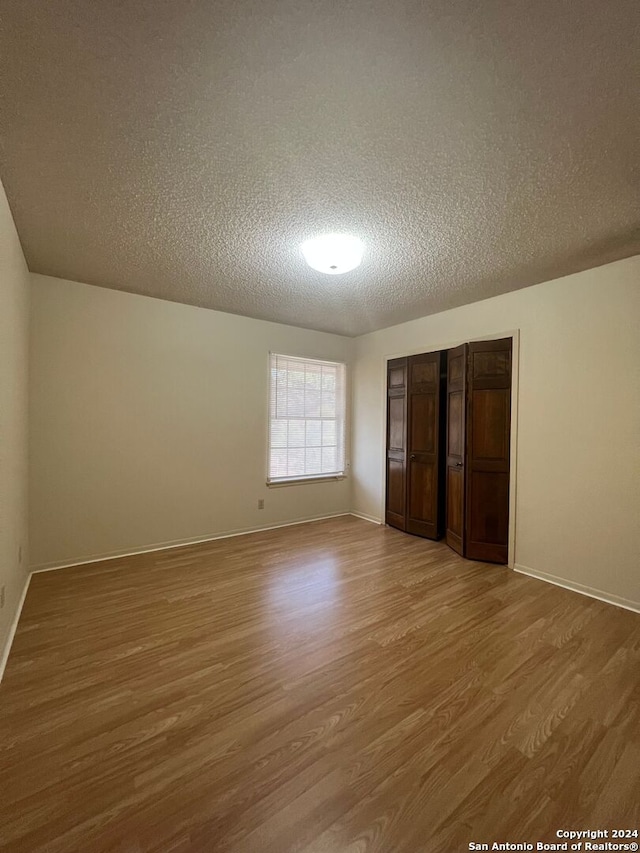 unfurnished bedroom featuring light hardwood / wood-style flooring, a textured ceiling, and a closet