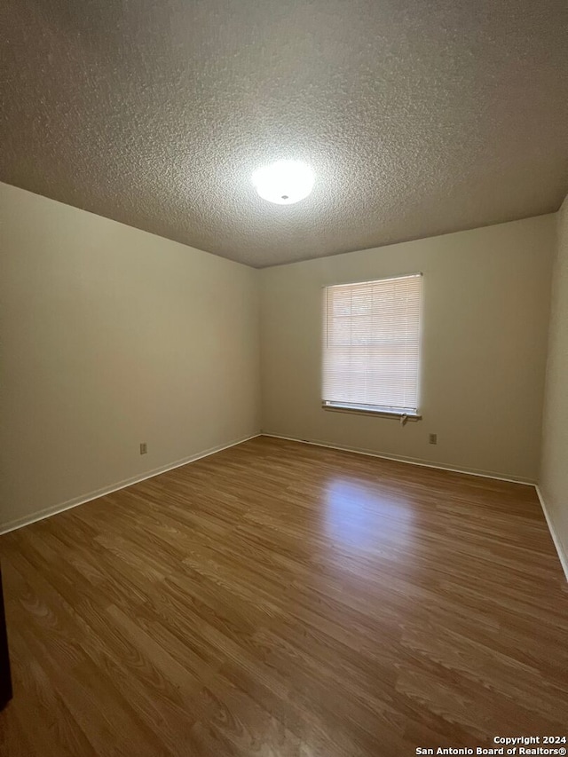 empty room with a textured ceiling and wood-type flooring