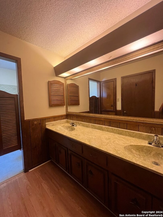 bathroom with vanity, wood walls, a textured ceiling, and hardwood / wood-style flooring