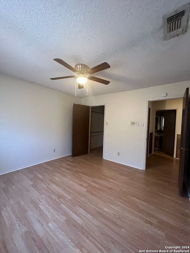 spare room with a textured ceiling, light wood-type flooring, and ceiling fan