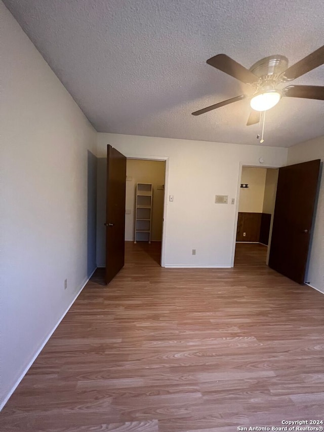 unfurnished room with ceiling fan, a textured ceiling, and light hardwood / wood-style flooring