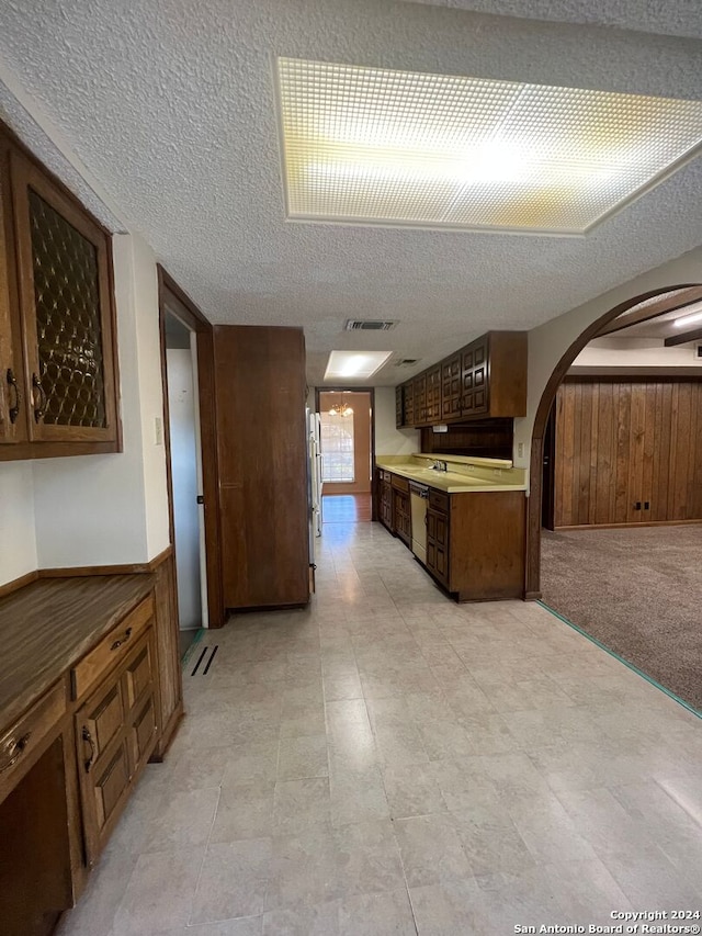 kitchen featuring light carpet, a textured ceiling, and dishwasher