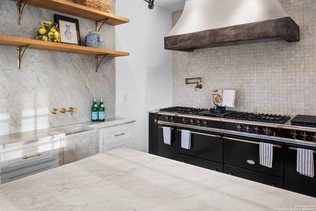 kitchen featuring white cabinetry, tasteful backsplash, wall chimney range hood, and double oven range