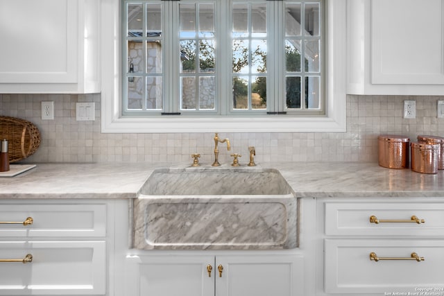 kitchen with sink, decorative backsplash, light stone countertops, and white cabinetry