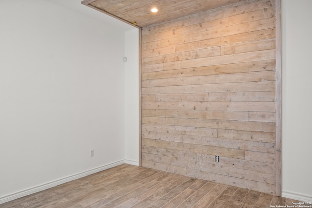 empty room with wood ceiling, hardwood / wood-style flooring, and wooden walls