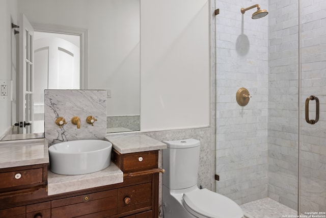 bathroom with tile walls, vanity, toilet, and an enclosed shower