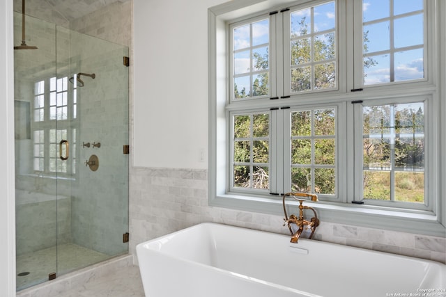 bathroom with tile walls, a wealth of natural light, and shower with separate bathtub