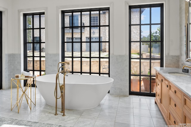 bathroom featuring vanity, tile walls, a washtub, and a wealth of natural light