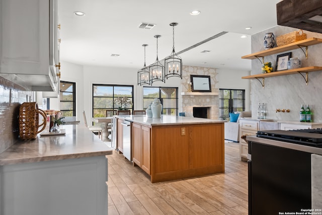 kitchen with a fireplace, light hardwood / wood-style flooring, a kitchen island, and white cabinets