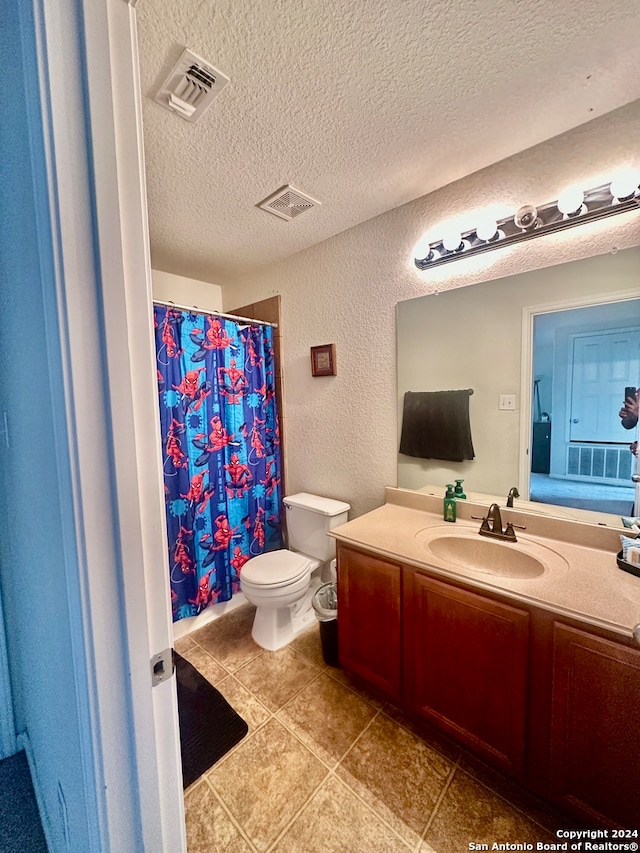 bathroom featuring tile patterned floors, toilet, a shower with curtain, vanity, and a textured ceiling