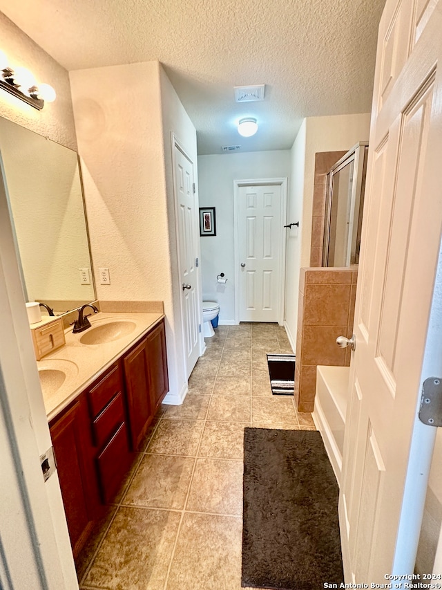 full bathroom featuring a textured ceiling, independent shower and bath, toilet, vanity, and tile patterned floors