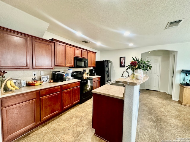 kitchen featuring sink, black appliances, a kitchen island with sink, and a textured ceiling