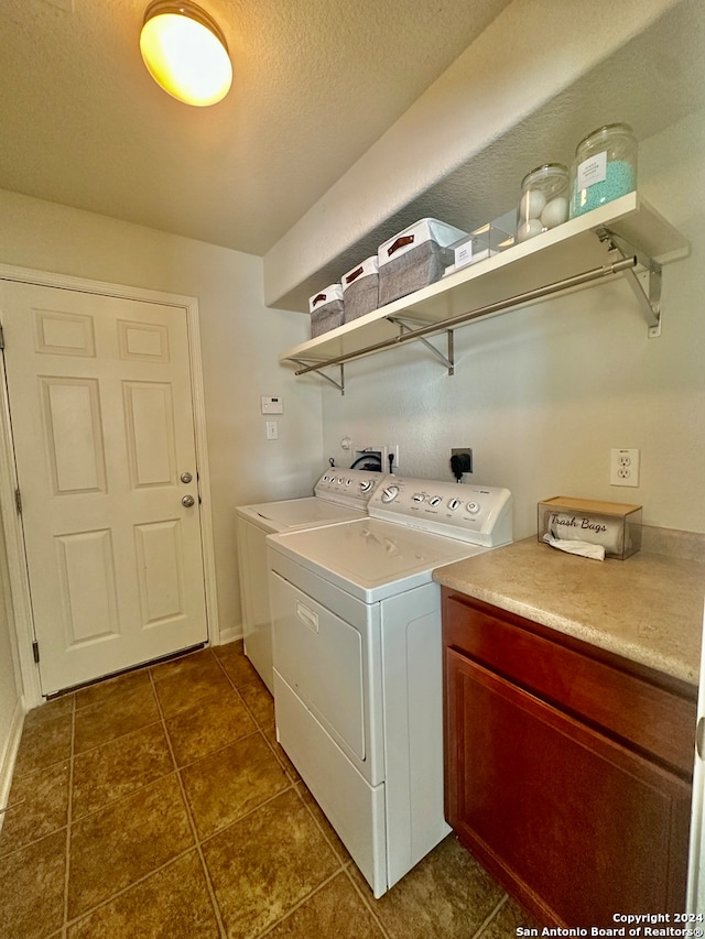 laundry area featuring dark tile patterned flooring, a textured ceiling, cabinets, and separate washer and dryer