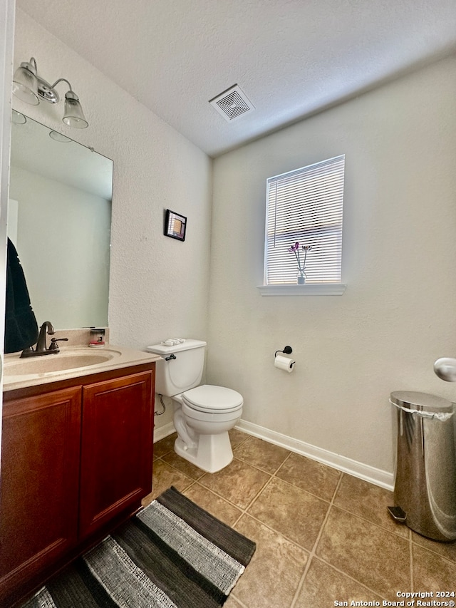 bathroom featuring vanity, toilet, tile patterned floors, and a textured ceiling