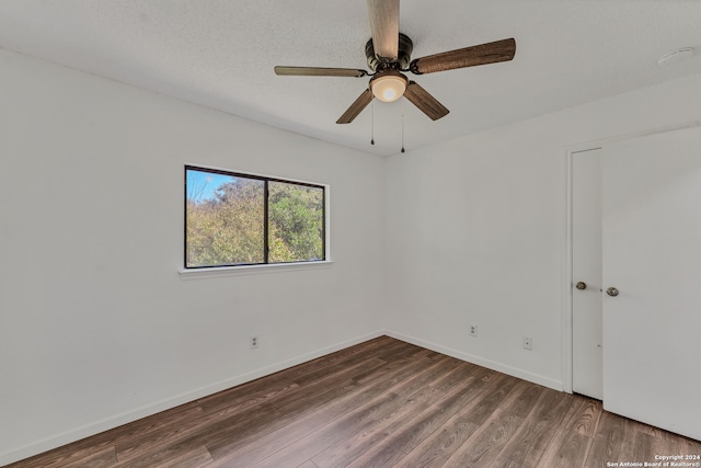 empty room with dark hardwood / wood-style flooring, a textured ceiling, and ceiling fan