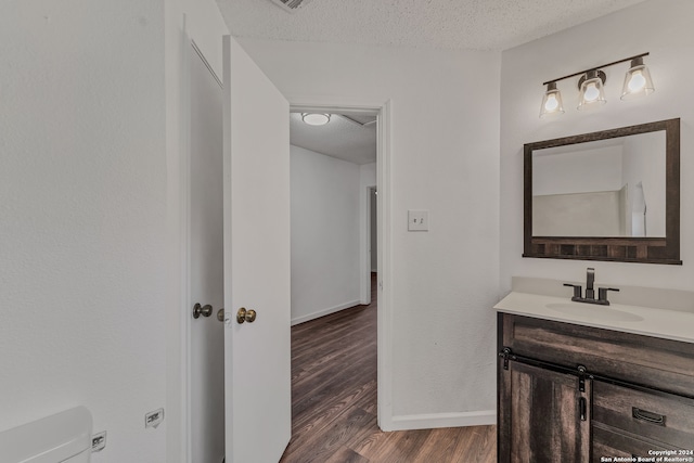 bathroom with toilet, vanity, a textured ceiling, and hardwood / wood-style flooring