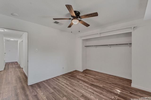 unfurnished bedroom featuring dark wood-type flooring, ceiling fan, a textured ceiling, and a closet